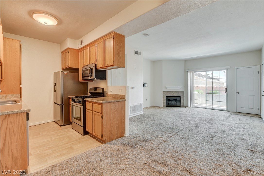 3318 North Decatur Boulevard, Unit 1069 Las Vegas, NV 89130 - Photo 9 of 39 A streamlined kitchen flows into a well-lit living area featuring a cozy fireplace.