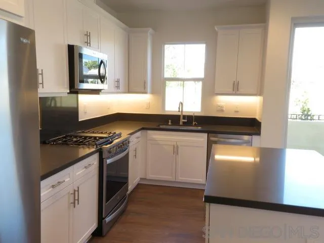 4382 Pacifica Way, Unit 5 Oceanside, CA 92056 - Photo 15 of 35 a kitchen with granite countertop cabinets stainless steel appliances and a window