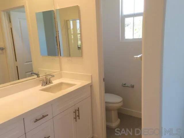 4382 Pacifica Way, Unit 5 Oceanside, CA 92056 - Photo 31 of 35 a bathroom with a granite countertop sink a toilet and a mirror