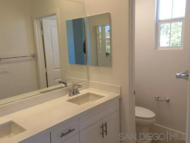 4382 Pacifica Way, Unit 5 Oceanside, CA 92056 - Photo 32 of 35 a bathroom with a granite countertop sink toilet and mirror
