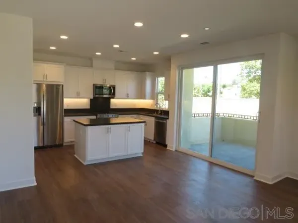 a kitchen with stainless steel appliances granite countertop a refrigerator a sink a stove a microwave and island with wooden floor