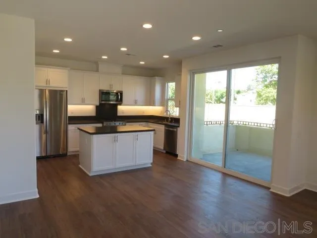 4382 Pacifica Way, Unit 5 Oceanside, CA 92056 - Photo 9 of 35 a kitchen with stainless steel appliances granite countertop a refrigerator a sink a stove a microwave and island with wooden floor