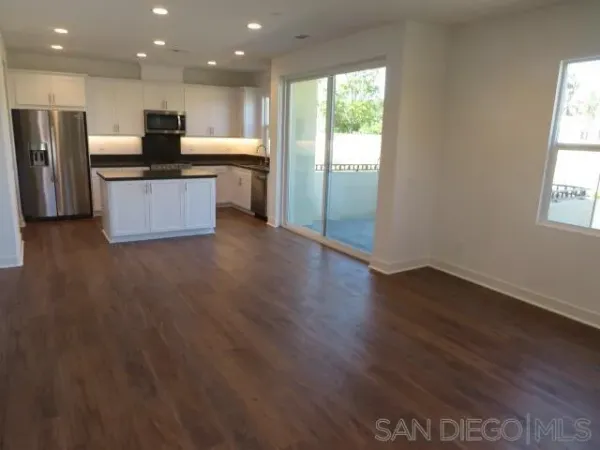 a kitchen with stainless steel appliances granite countertop a refrigerator a sink dishwasher a stove and a large countertops with wooden floor