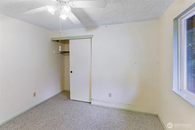 an empty room with a ceiling fan and a window