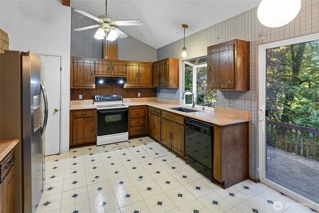 a kitchen with a sink a stove a refrigerator and black cabinets