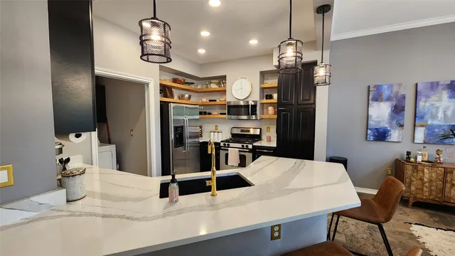 a kitchen with stainless steel appliances kitchen island granite countertop a refrigerator a microwave oven a sink with a dining table and chairs