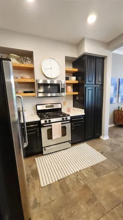 a kitchen with stainless steel appliances kitchen island granite countertop a refrigerator a stove and a sink