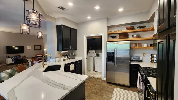a kitchen with stainless steel appliances kitchen island granite countertop a refrigerator a stove and a sink with wooden floor