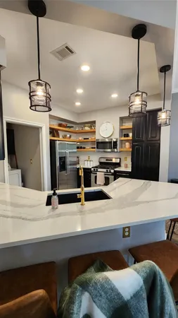 a kitchen with stainless steel appliances kitchen island granite countertop a sink a stove and a refrigerator