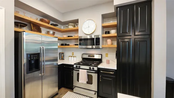 a kitchen with stainless steel appliances granite countertop a refrigerator a oven and a sink with wooden floor