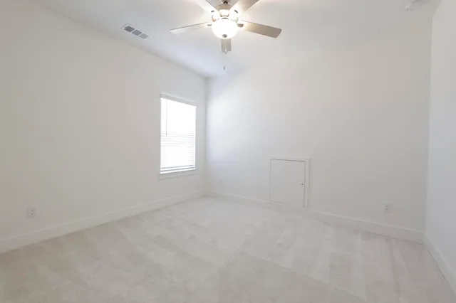 an empty room with a chandelier fan and windows