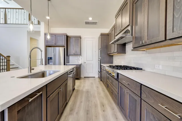 a kitchen with stainless steel appliances granite countertop a sink a stove and a refrigerator