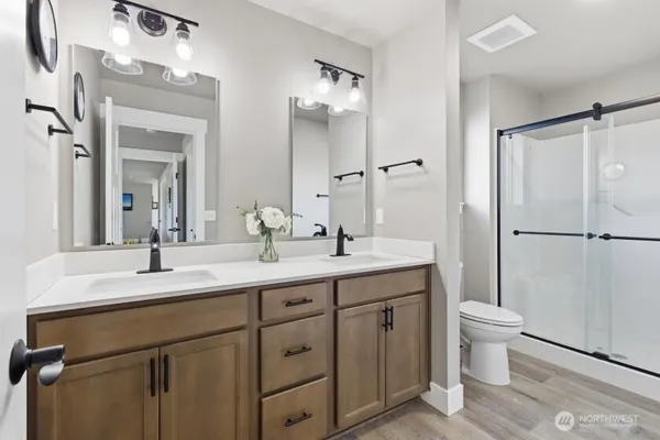 a bathroom with a double vanity sink toilet and a mirror