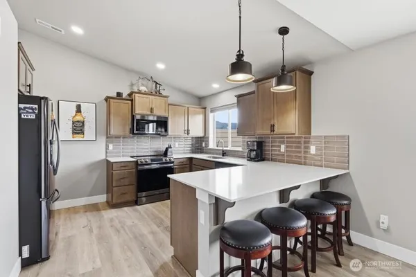 a large kitchen with granite countertop stools a sink stainless steel appliances and cabinets