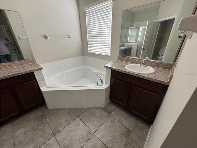a bathroom with a granite countertop bathtub sink and mirror