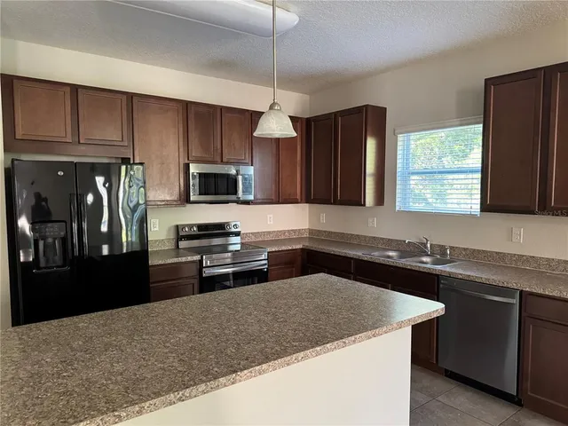 a kitchen with a sink stove top oven and refrigerator