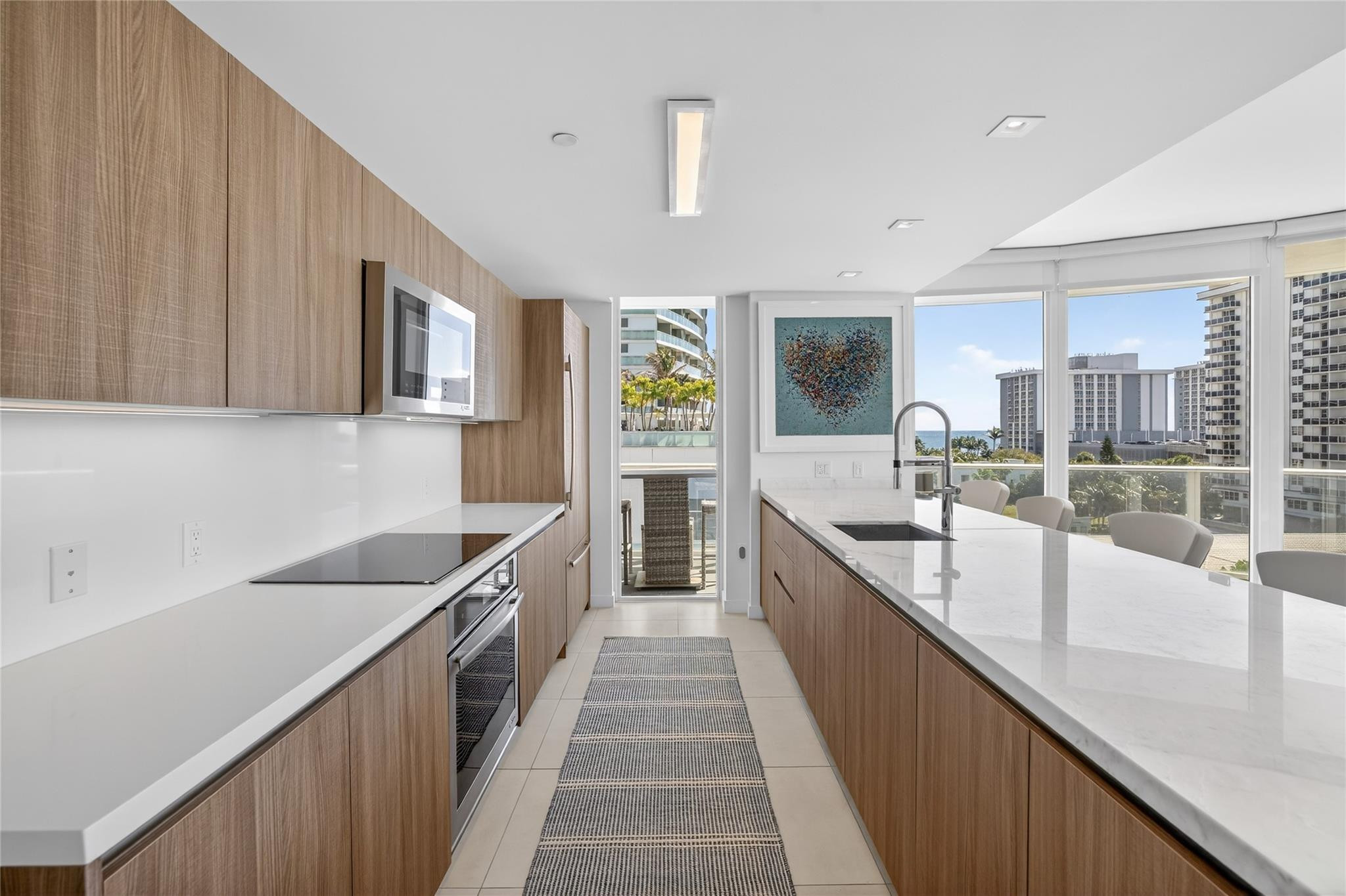 401 North Birch Road, Unit 600 Fort Lauderdale, FL 33304 - Photo 9 of 47 a large white kitchen with kitchen island a large counter top space a sink a window and stainless steel appliances