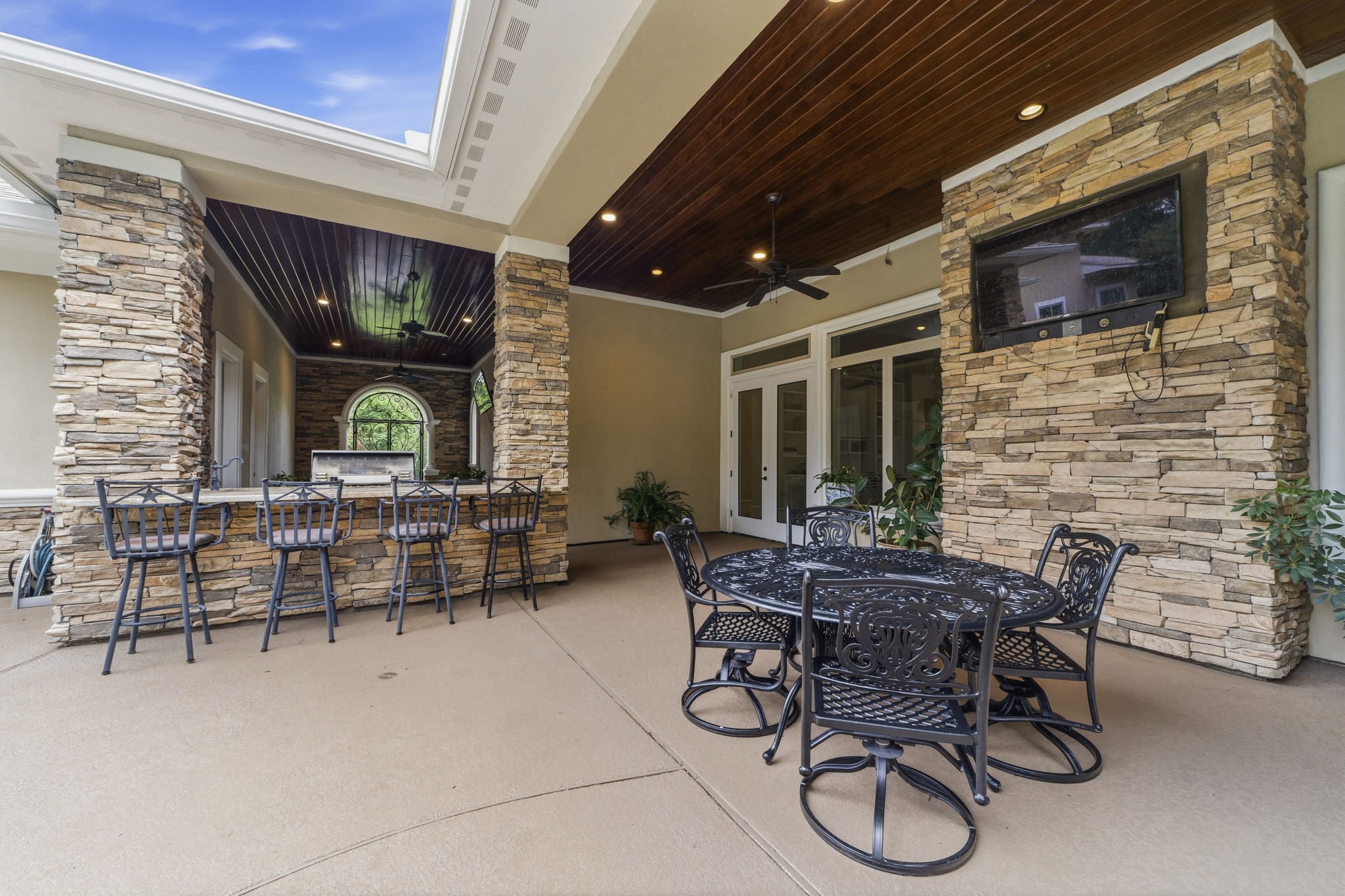 27402 Jacob's Path Lane Spring, TX 77386 - Photo 8 of 48 This view highlights the impressive outdoor backyard living area, showcasing the spacious covered veranda designed for year-round enjoyment. Features include a dedicated space for an outdoor television, a summer kitchen complete with a built-in grill, and elevated countertop seating perfect for casual dining and entertaining. The thoughtful layout creates an ideal setting for gathering with family and friends while enjoying the beauty of the backyard.