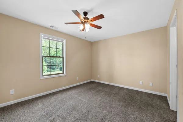 an empty room with ceiling fan and windows