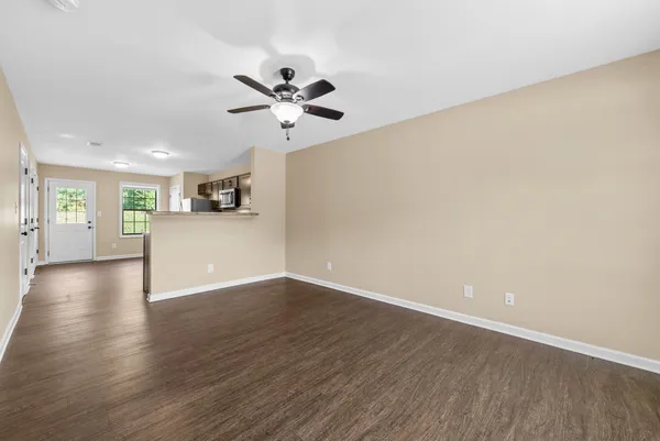 a view of an empty room with wooden floor and a window