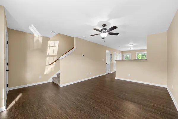 a view of an empty room with wooden floor and a ceiling fan