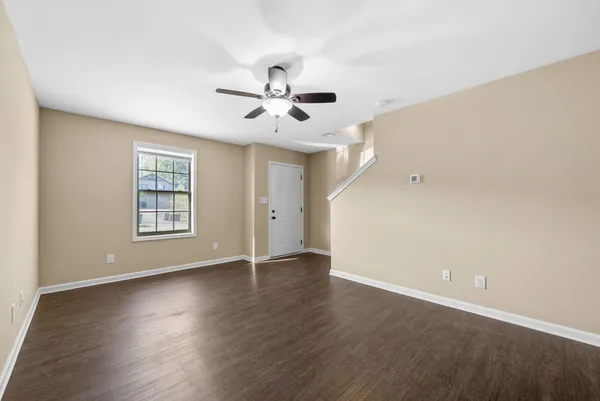 an empty room with wooden floor ceiling fan and windows