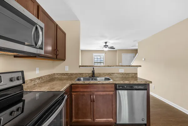 a kitchen with granite countertop a sink stove and microwave