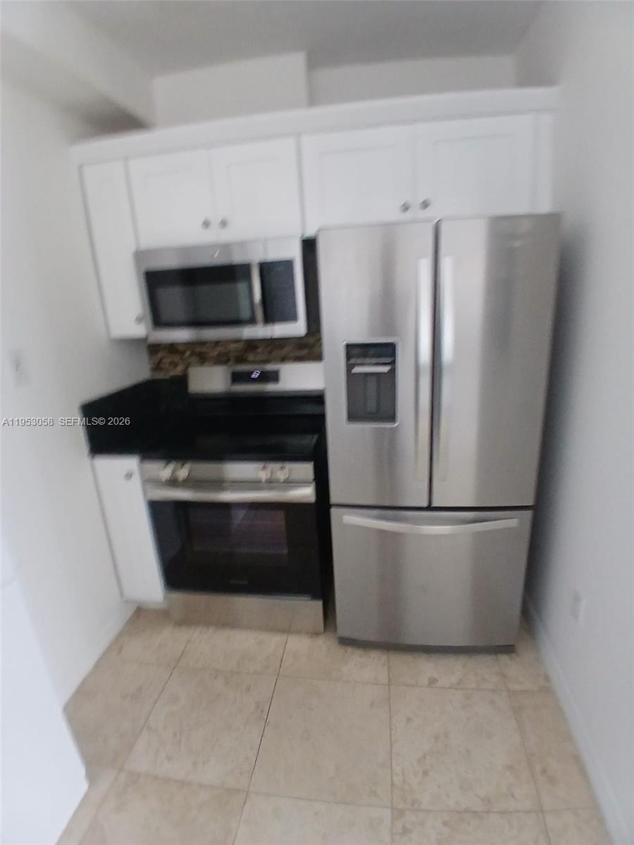 425 Northeast 30th Street, Unit 202 Miami, FL 33137 - Photo 9 of 11 a kitchen with a stove a refrigerator and a microwave