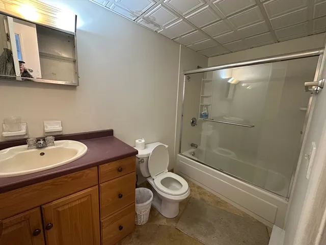 a bathroom with a granite countertop sink toilet a mirror and shower