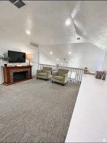 838 East Mountain Road North Ogden, UT 84414 - Photo 24 of 37 Upper-level bonus room featuring recessed lighting, textured carpeting, and a built-in electric fireplace with a stone-tile surround