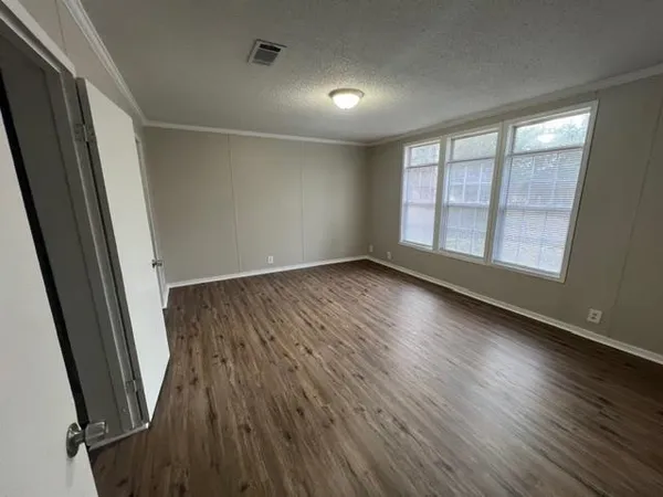 an empty room with wooden floor and windows