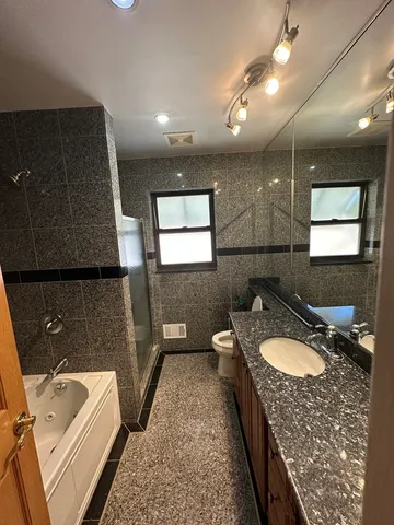 a bathroom with a granite countertop double vanity sink a mirror and a bathtub