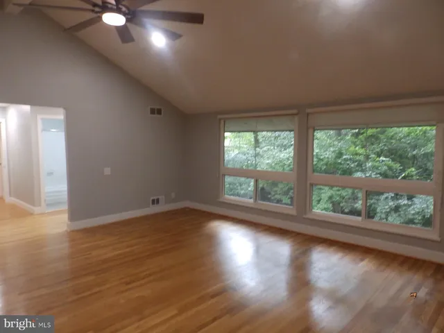 a view of an empty room with wooden floor and a window