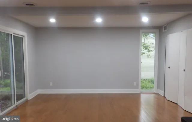 an empty room with wooden floor and windows