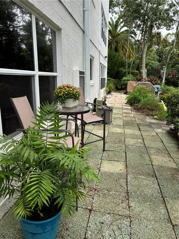 a backyard of a house with table and chairs potted plants and large tree