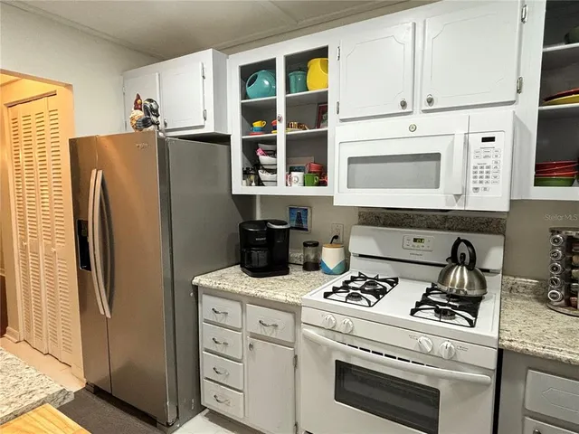 a kitchen with appliances a refrigerator and cabinets