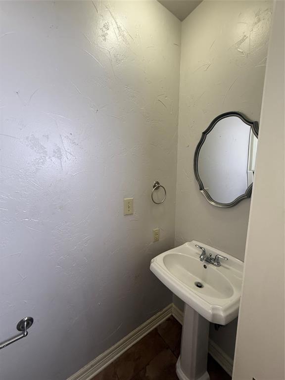 201 Woodhaven Drive Minden, LA 71055 - Photo 23 of 31 Compact bathroom featuring a white pedestal sink with a chrome faucet, a decorative framed mirror, and textured wall finishes