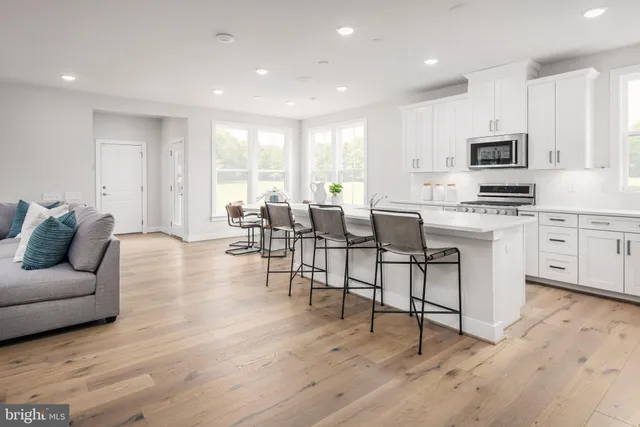 a living room with furniture a flat screen tv and kitchen view