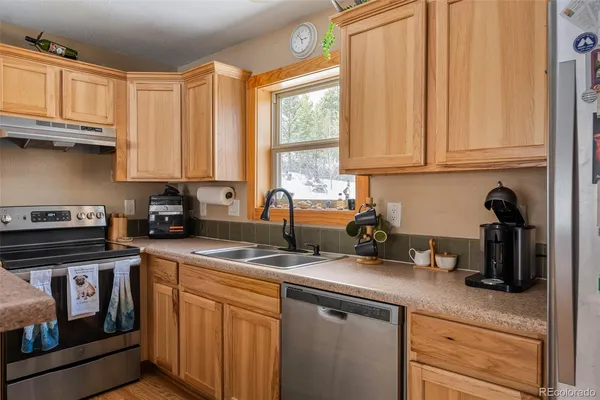 a kitchen with stainless steel appliances granite countertop a sink a stove and a refrigerator