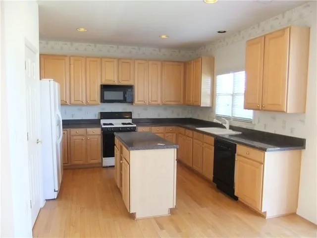 a kitchen with a sink a stove top oven a refrigerator and a window