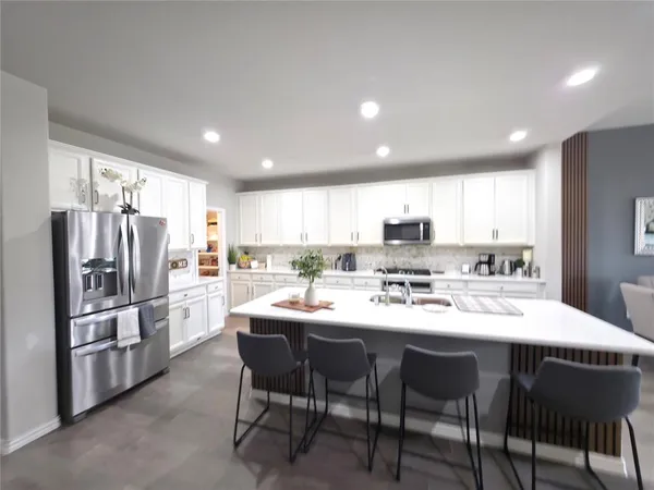 a kitchen with stainless steel appliances granite countertop a dining table chairs refrigerator sink and cabinets