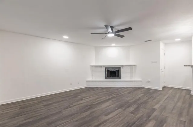 a view of an empty room with wooden floor and a ceiling fan