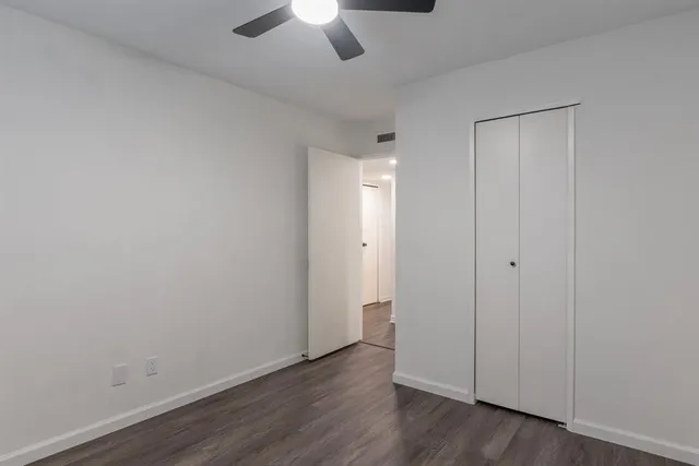 an empty room with wooden floor and a ceiling fan