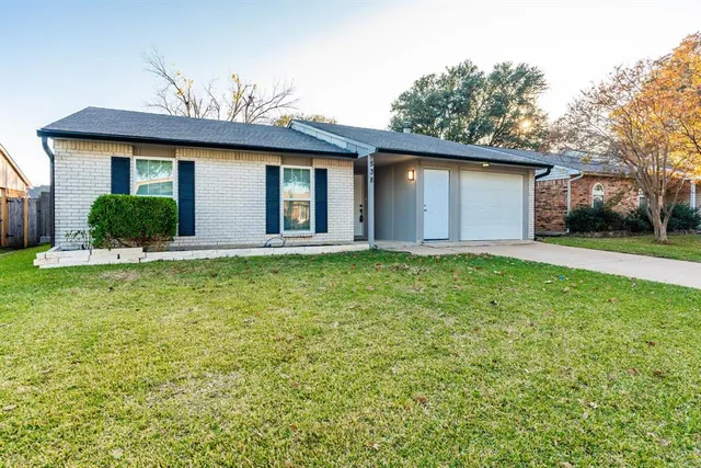 a front view of house with yard and trees in the background