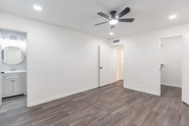 an empty room with wooden floor and ceiling fan