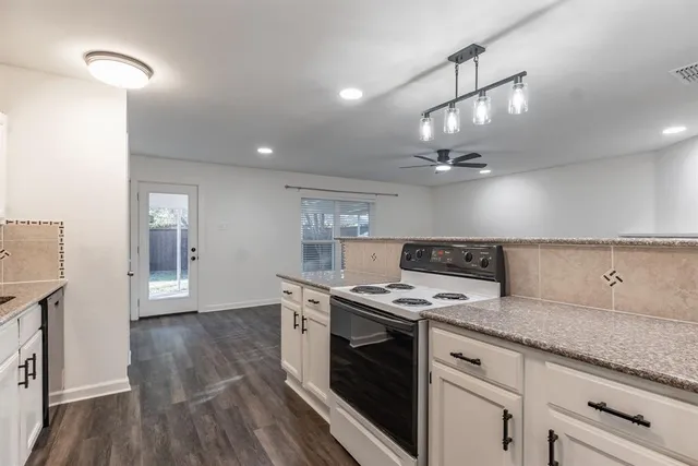 a kitchen with granite countertop a sink cabinets and stainless steel appliances