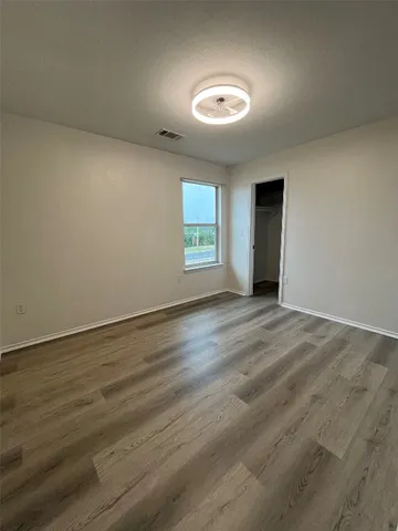 an empty room with wooden floor and windows