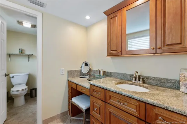 a bathroom with a granite countertop sink and a toilet