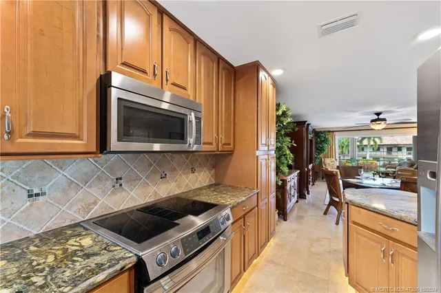 a kitchen with stainless steel appliances granite countertop a stove a sink and a microwave