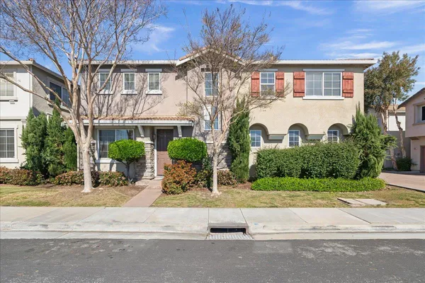 a view of a white house with a large tree